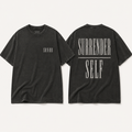 Two views of a washed black t-shirt on a light beige background. The front view shows a small white 'SANDR' logo on the left chest, and the back view features a large distressed white graphic reading 'SURRENDER SELF' with a horizontal line.